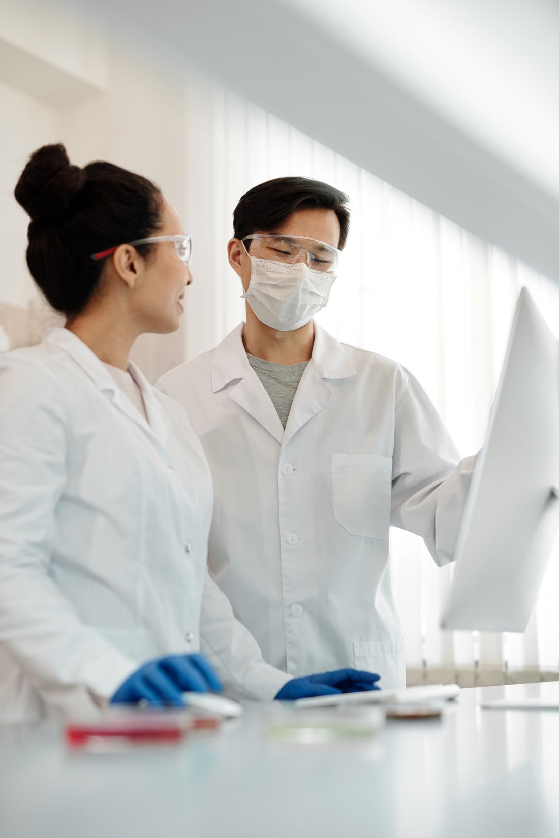 Researchers wearing laboratory safety equipment discussing work at a computer