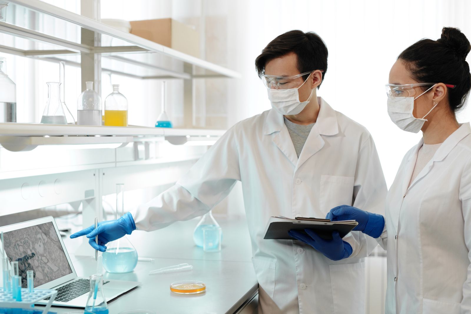 Two scientists examining research images on a laptop in a laboratory